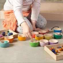 Child sorting objects in 12 differently colored bowls in a play setting