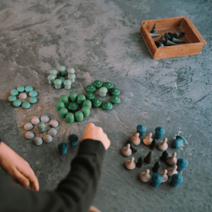 Child arranging small wooden shapes on a textured surface