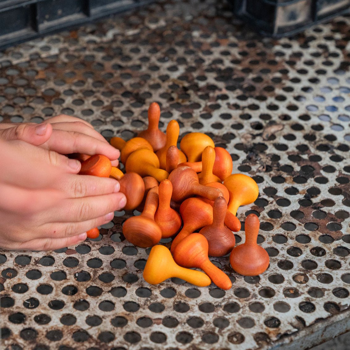 hand scooping pile of orange play pieces on a silver grate
