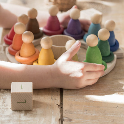 child interacting with wooden perpetual calendar with 12 differently colored peg people arranged in a circle