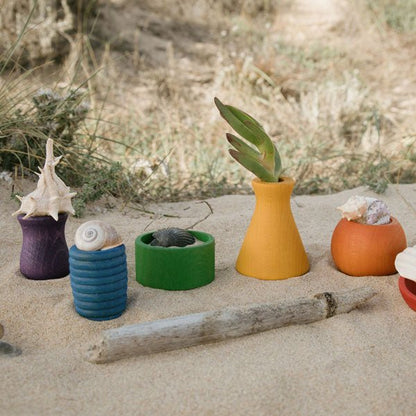 Colorful wooden planters with shells and a plant on a sandy surface