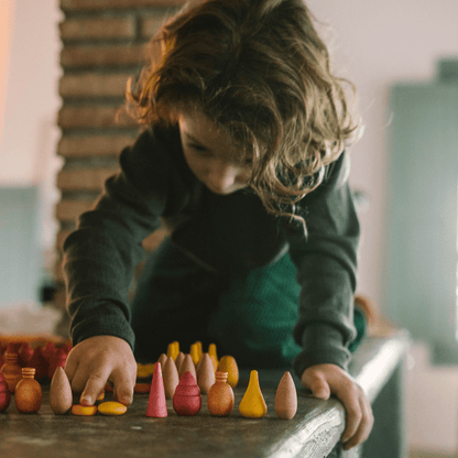 Child playing with colorful wooden toys on a table.