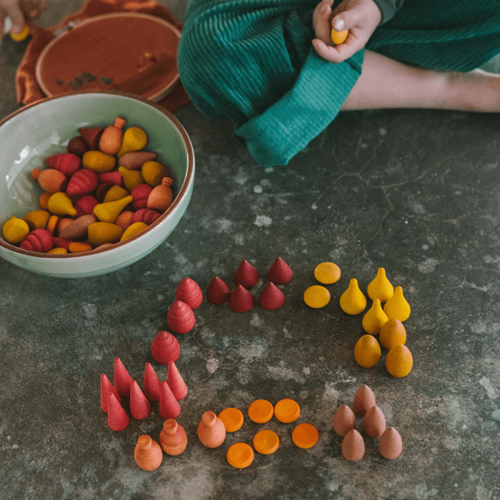 Child playing with colorful wooden shapes on a concrete floor