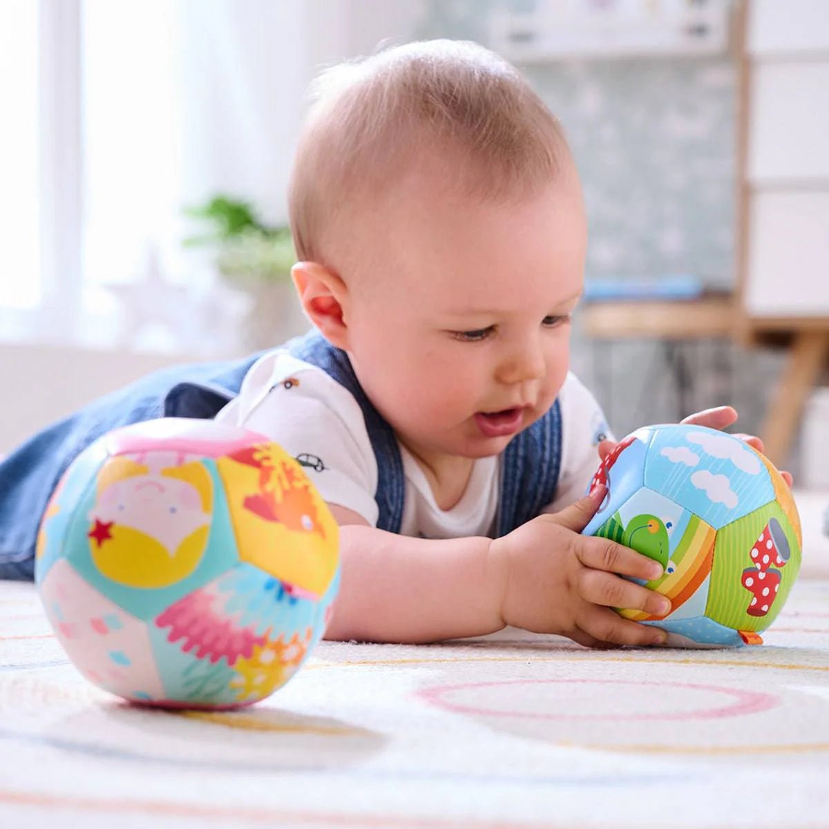 Baby playing with colorful soft balls on a light colored rug