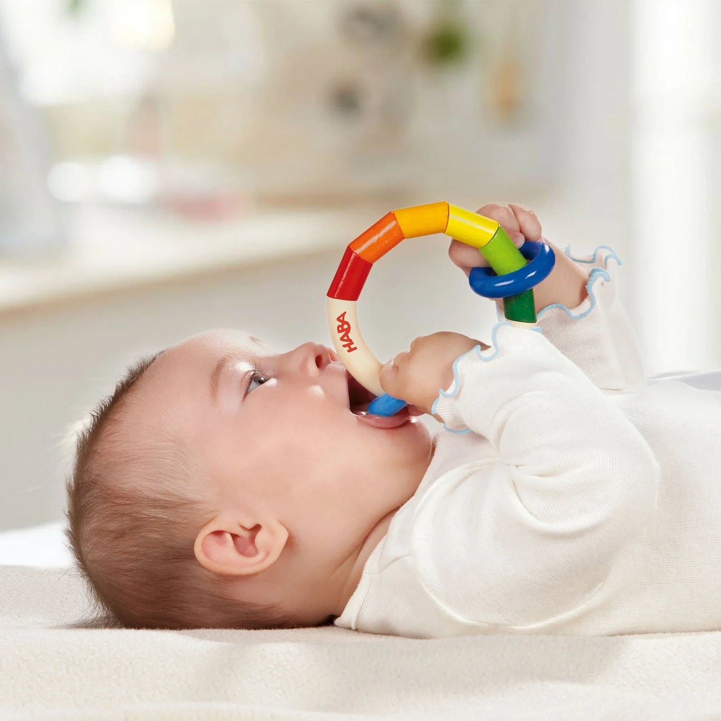 Baby playing with a colorful toy ring on a blurred background