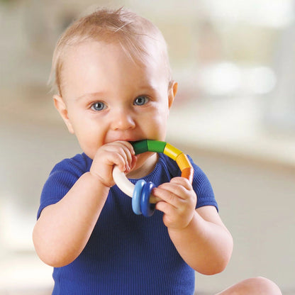 Baby holding a colorful teething ring with a blurred background