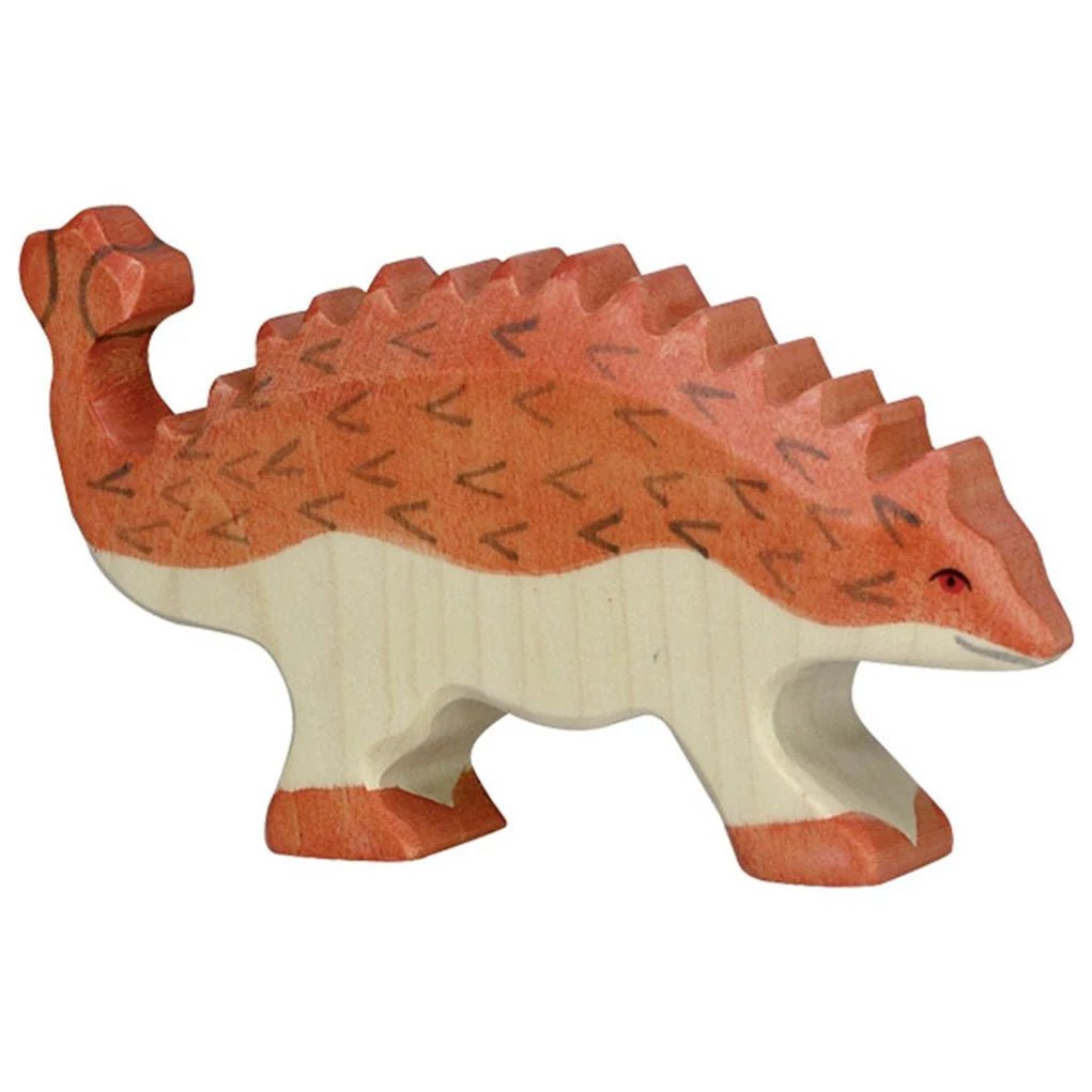 Wooden toy ankylosaurus dinosaur with red and white design on a white background