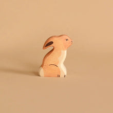Wooden tan rabbit sitting upright against a light colored background