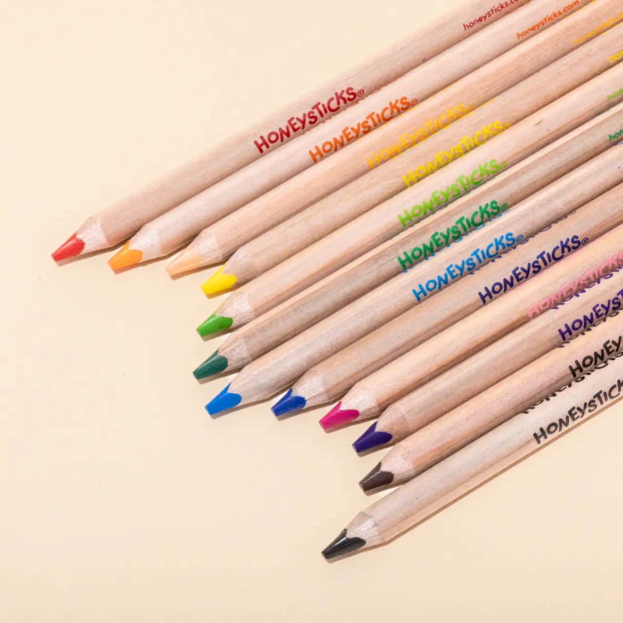 Colorful pencils with 'Honeysticks' branding on a beige background