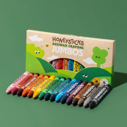 A box of Honeysticks Beeswax Crayons Jumbos with multiple colorful crayons arranged in front on a solid green background.