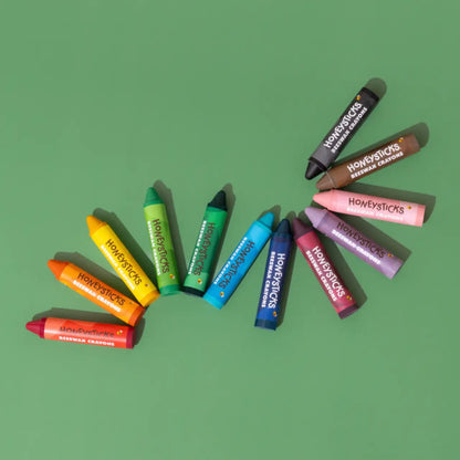 Honeysticks super jumbo crayons arranged in a wavy line on a green background