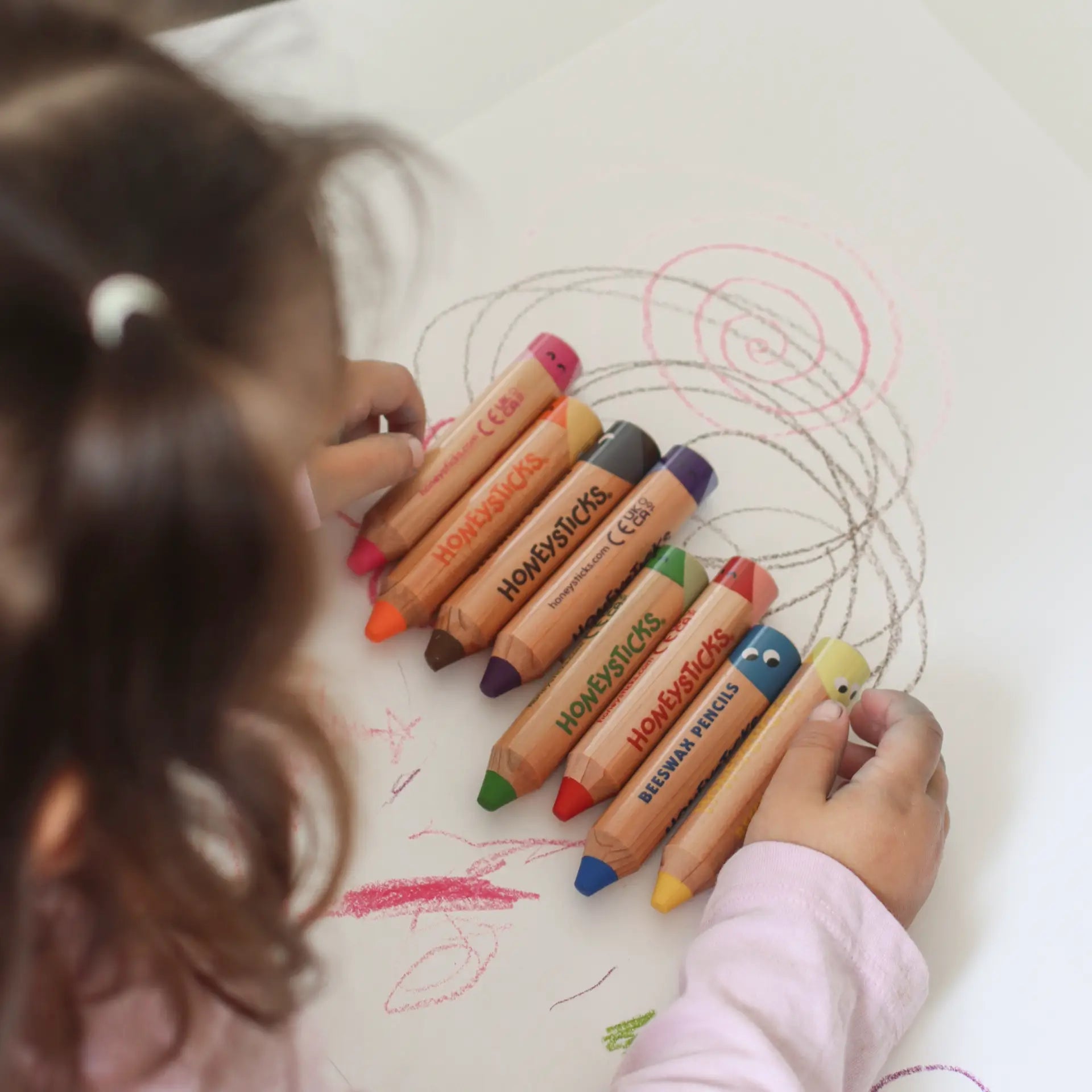 Child drawing with colorful Honeysticks pencils on a piece of paper