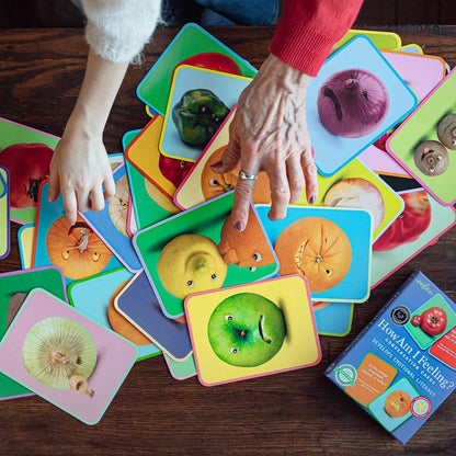 Children's educational game with colorful cards featuring fruits and vegetables on a wooden table.