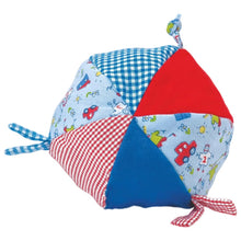 A handmade fabric ball with patchwork panels in red, blue, white, and a light blue cartoon print, shown on a plain white background.