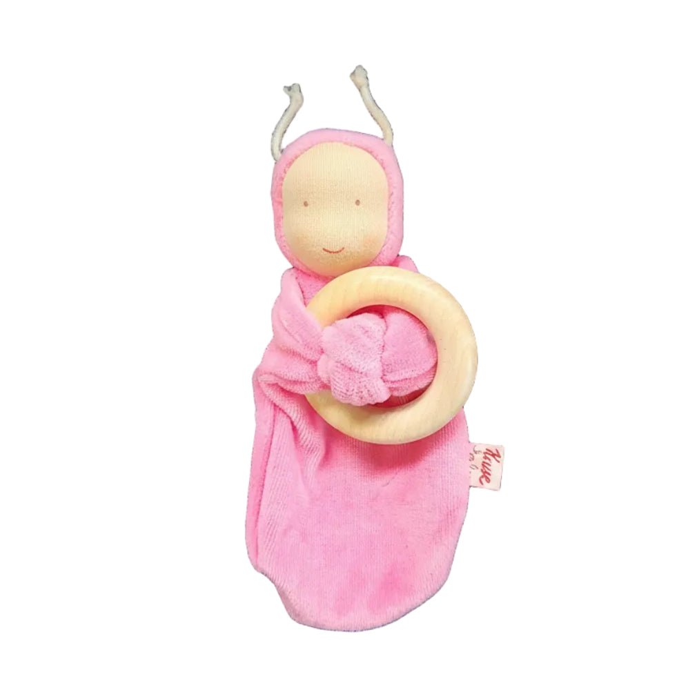 A pink plush baby lovey with a wooden ring rattle, featuring a smiling face on a white background