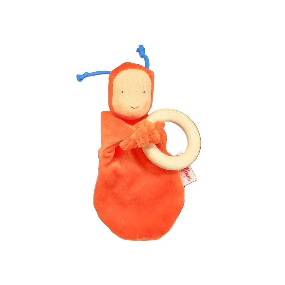 A baby teething toy featuring a soft orange-red wrapped doll with a wooden ring handle on a white background