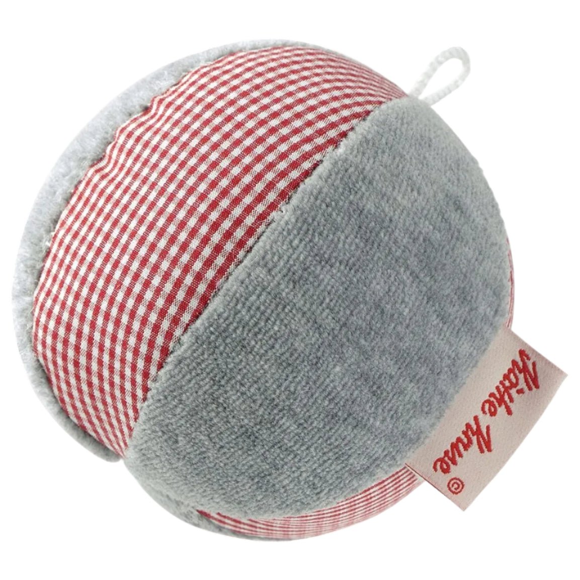 A round plush rattle ball with a red and white gingham pattern on one half and a solid light gray fabric on the other half, featuring a beige fabric tag with red script that reads 'Kathe Kruse'.