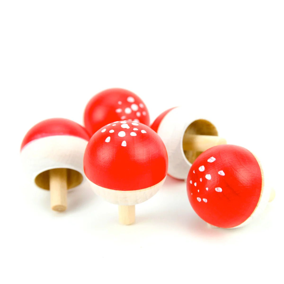 Wooden toy mushrooms tops with red caps and white spots on a white background
