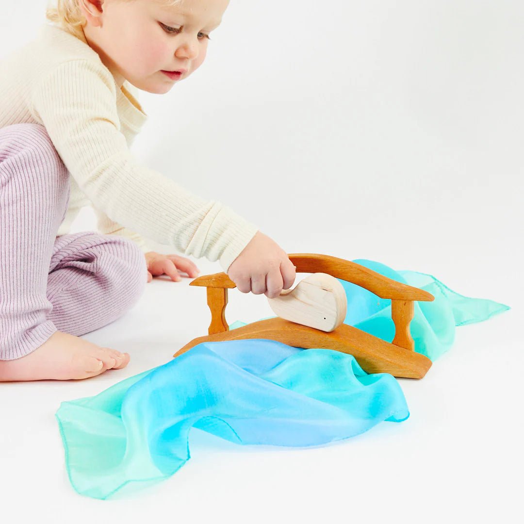 Child playing with a wooden toy on a white surface