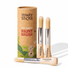Three paint brushes with a cardboard tube labeled 'Honeysticks' on a white background