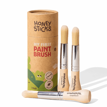 Three paint brushes with a cardboard tube labeled 'Honeysticks' on a white background
