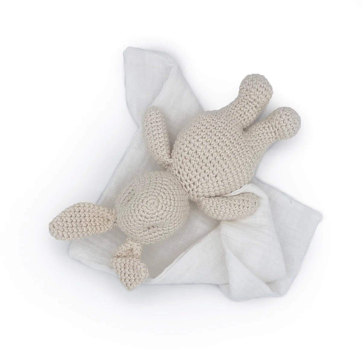 Crocheted bunny toy on a white blanket with a white background