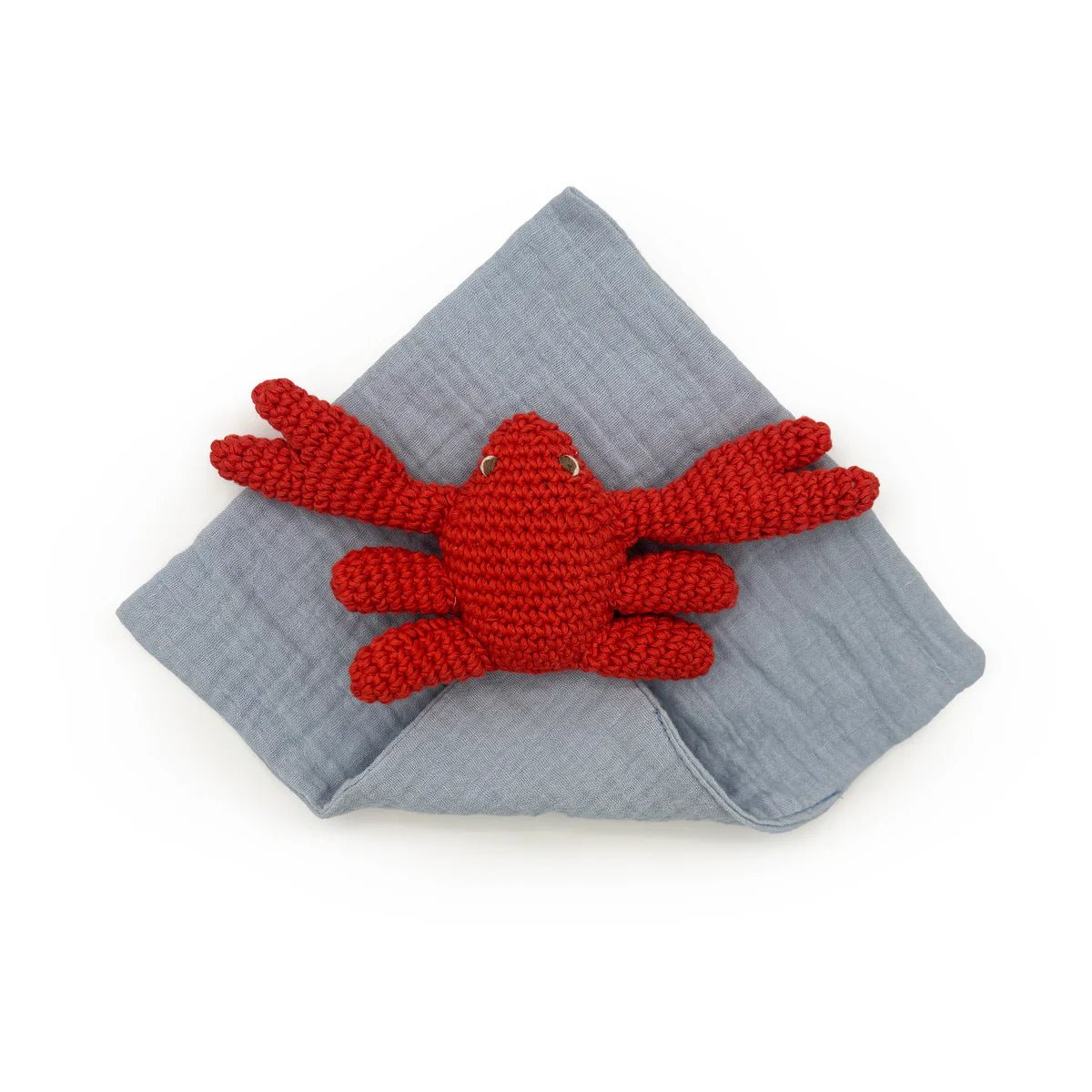 Red crocheted crab toy on a gray fabric background