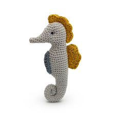 Crocheted seahorse toy with yellow dorsal fin on a white background