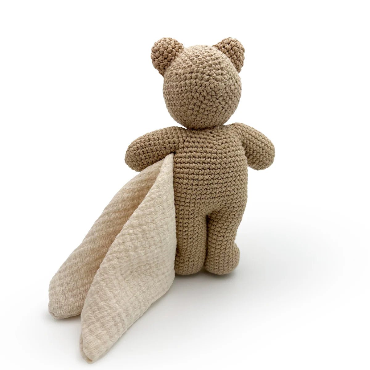 Back side of a crocheted bear toy with a soft blanket on a white background