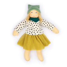 Doll wearing a polka dot shirt, green hat, and mustard yellow skirt on a white background