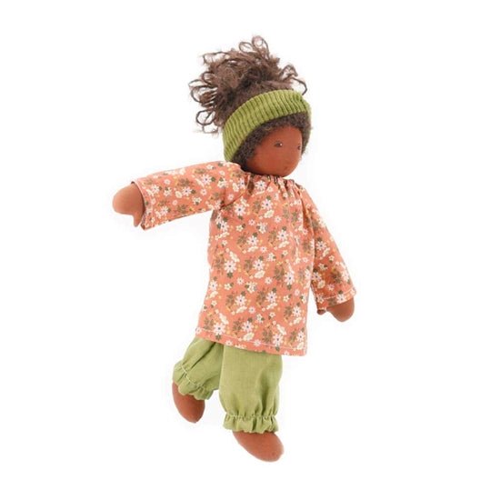 Nanchen doll with dark skin and pink and green floral clothing on a white background
