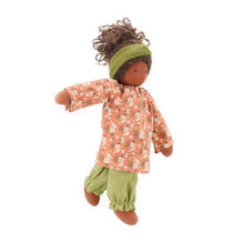 Nanchen doll with dark skin and pink and green floral clothing on a white background