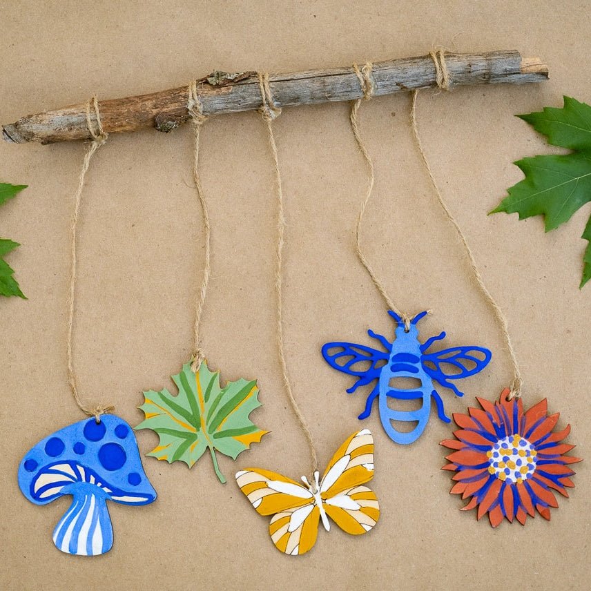 Decorative items including a blue mushroom, green leaf, yellow butterfly, and red flower hanging from a branch on a brown background.