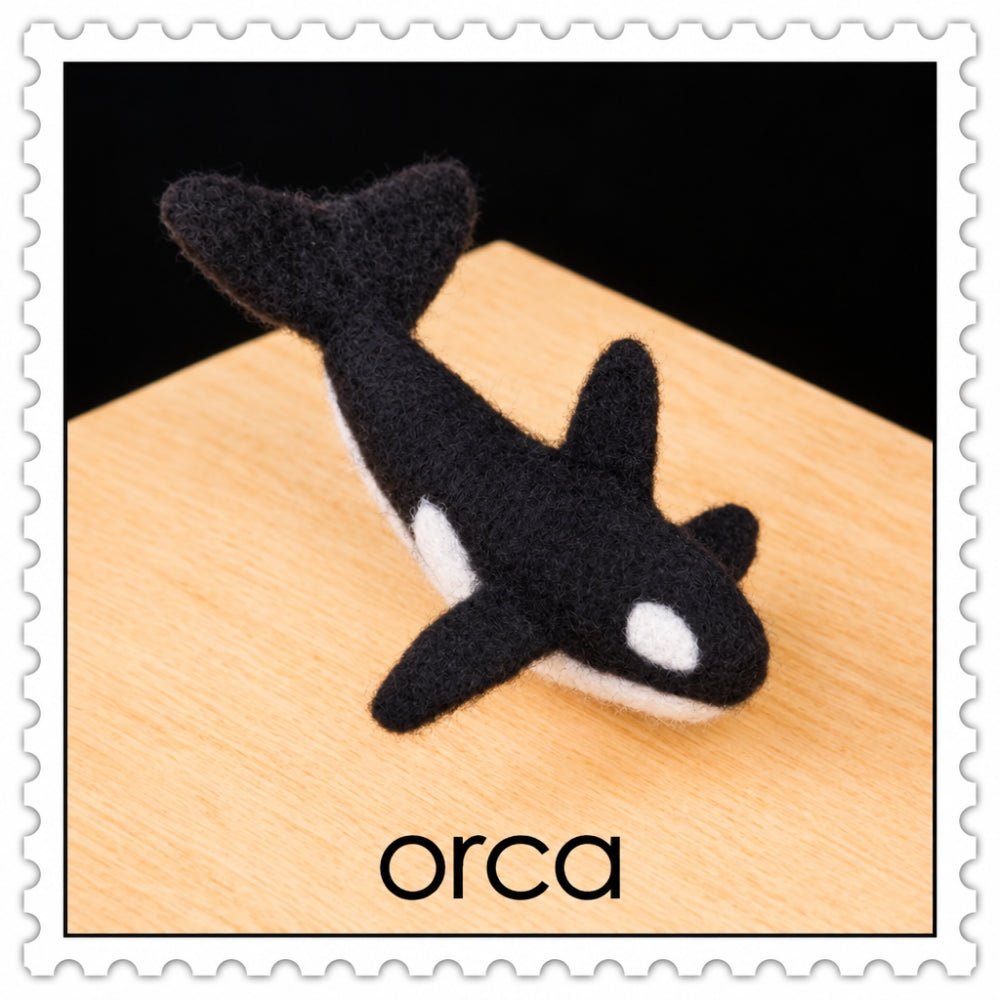 Felted orca on a wooden surface on a black background