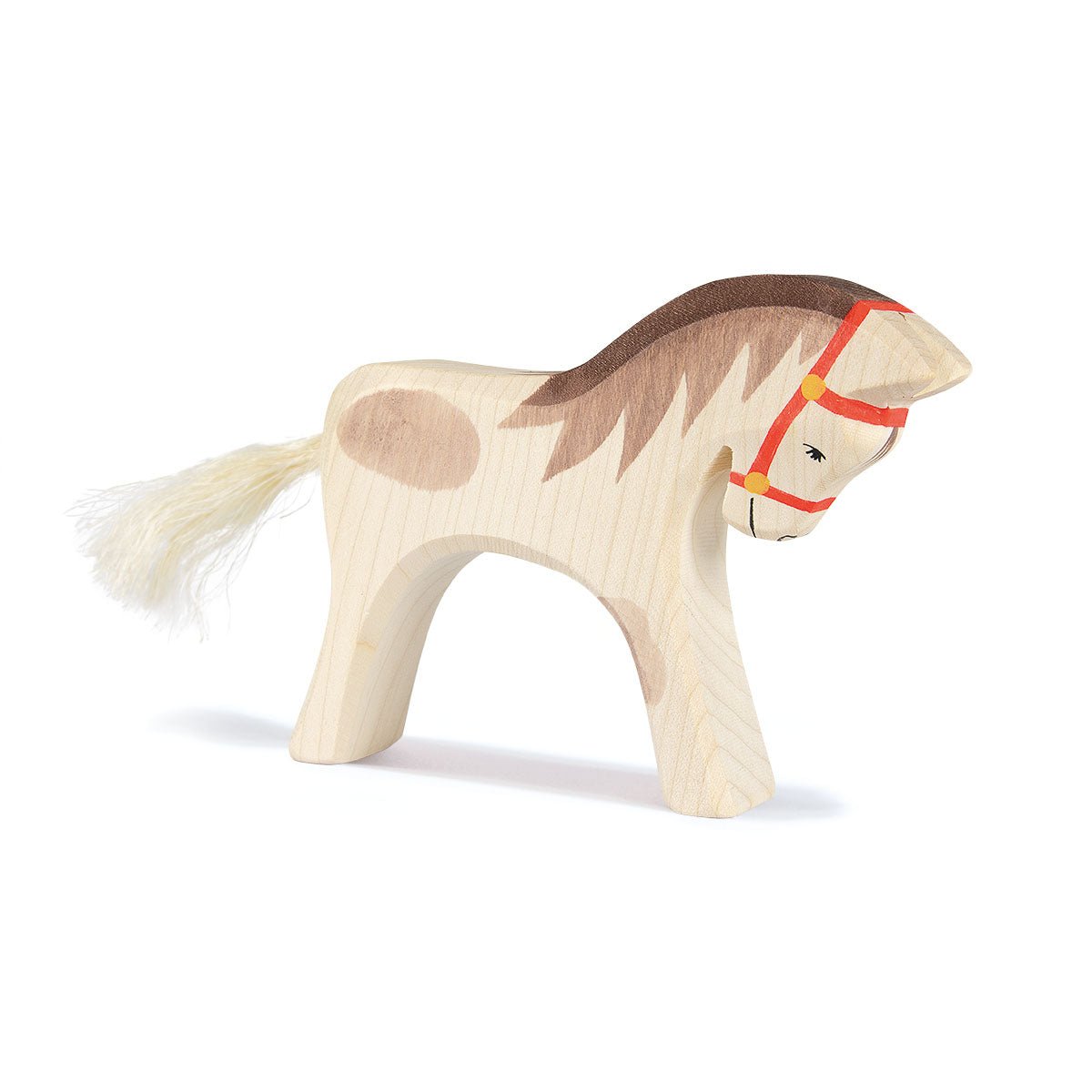 Wooden horse toy with a red bridle on a white background