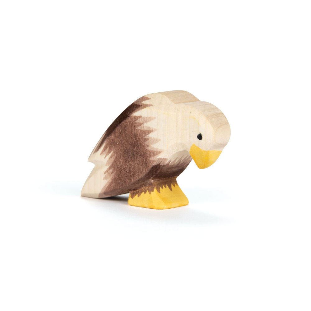 Wooden bald eagle figurine in a sitting position on a white background