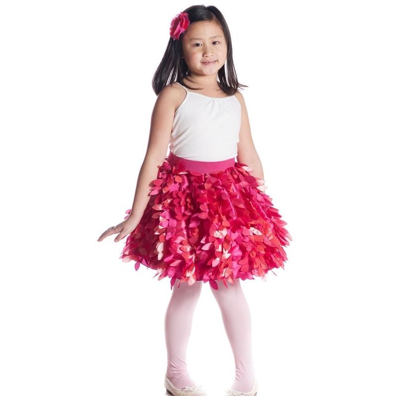 Young girl wearing a white top and pink floral skirt on a white background