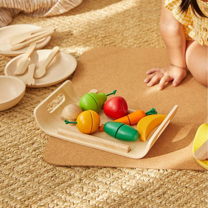 Child playing with wooden toy fruits and vegetables on a mat