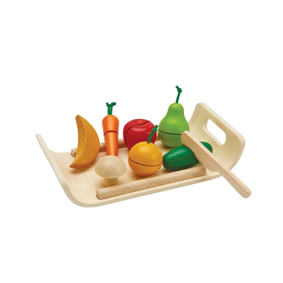 Colorful toy fruits and vegetables on a wooden tray with a knife on a white background