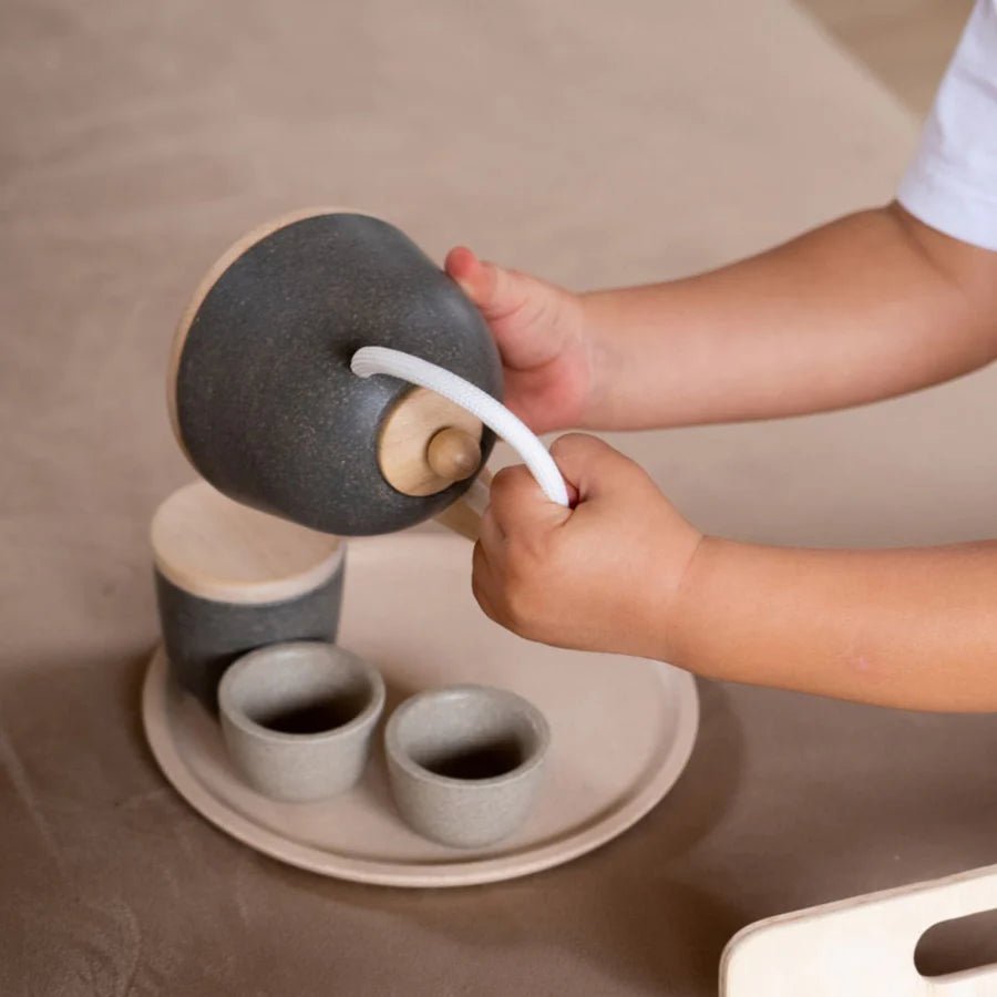Child pouring pretend tea from a gray teapot