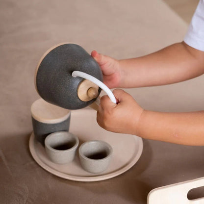 Child pouring pretend tea from a gray teapot
