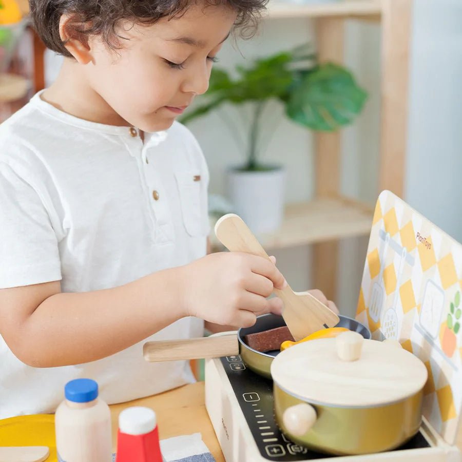 Child playing with toy kitchen set in a bright room
