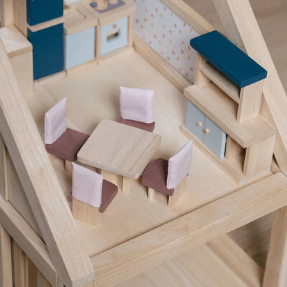 Dining room set up in a doll house with kitchen appliances and a table and chairs