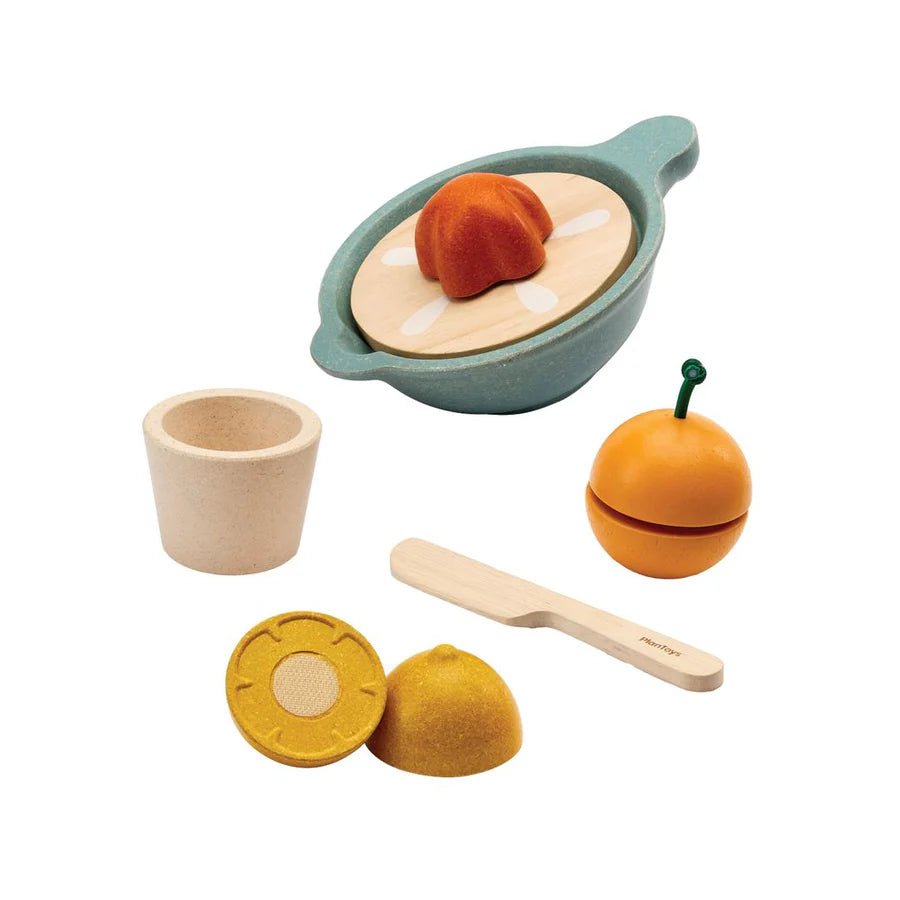 Set of wooden toy food items including a juice squeezer, a cup, and utensils on a white background