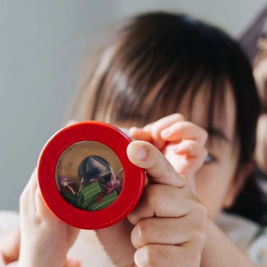 Child looking through a kaleidoscope with leaves and flowers inside of it