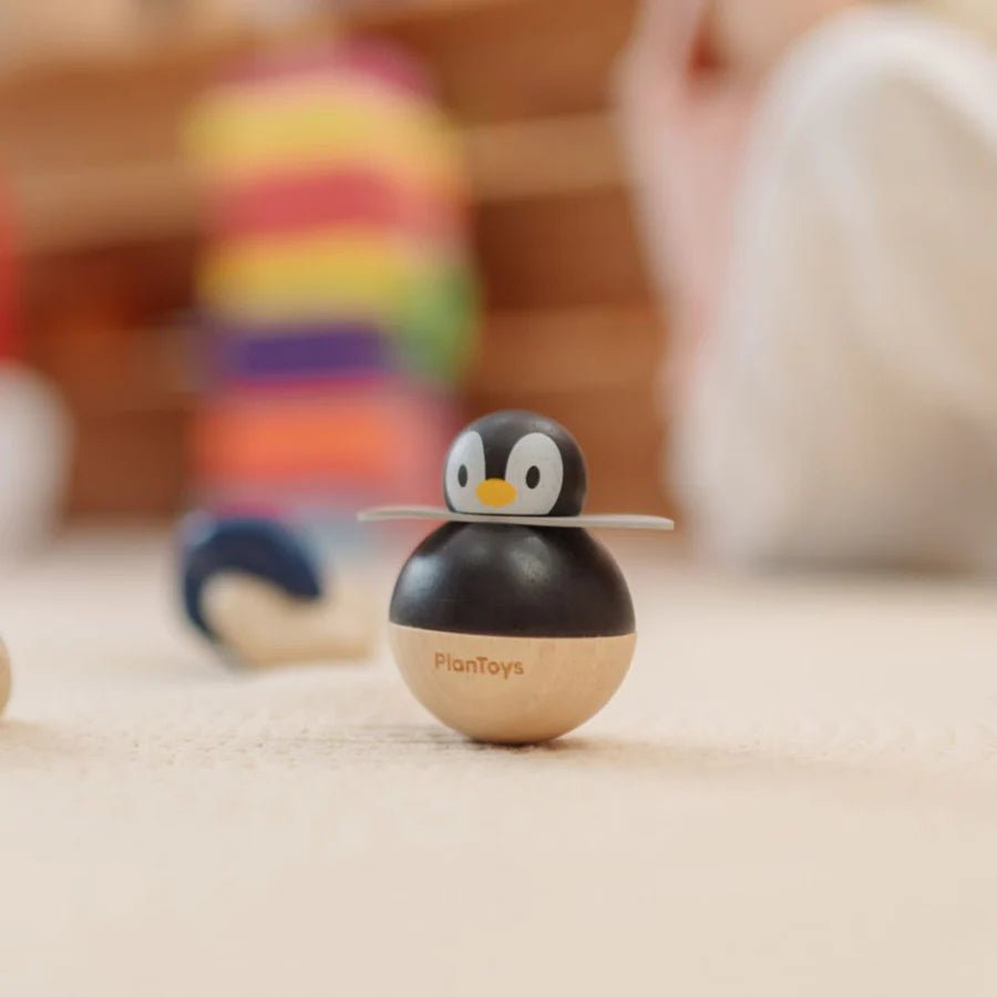 Wooden penguin toy with 'PlanToys' branding on a carpeted surface.