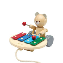 Wooden pull toy with a bear character playing a xylophone on a white background