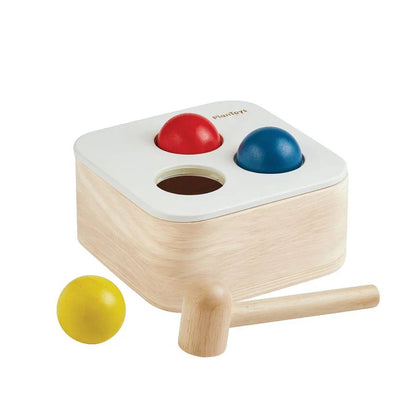 Wooden toy with colorful balls and a mallet on a white background