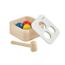 Wooden toy set with colorful balls, a mallet, and a removable lid on a white background