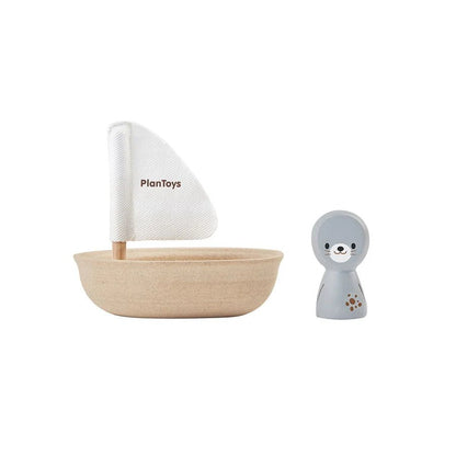 Wooden toy boat with white sail and a small gray seal figure on a white background, featuring the PlanToys brand.